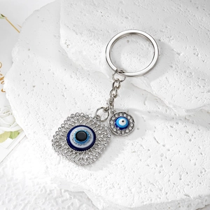 Macro shot of silver alloy Evil Eye keychain with shimmering rhinestones on white stone