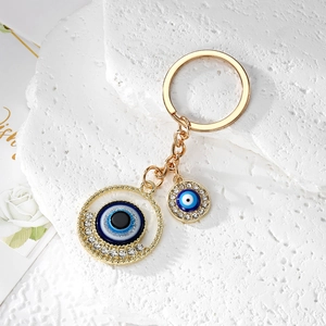 Detail of golden Evil Eye keychain with sparkling crystals and blue enamel charms on stone