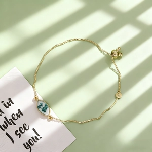 Vue détaillée du bracelet doré ajustable avec pendentif marquise en fleurs séchées vertes