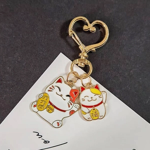 Gros plan de deux chats Maneki Neko avec un fermoir en forme de cœur doré brillant