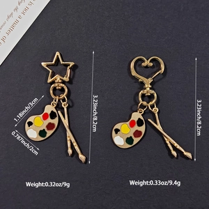 Detailed view of artist palette keychain charms with gold finish and colorful enamel dots