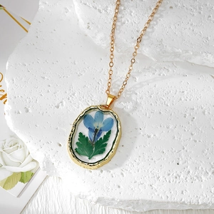 Pendentif ovale en résine avec vraies fleurs séchées bleues et cadre en métal martelé doré