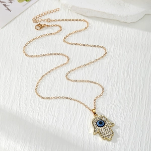 Hamsa Hand ketting met blauwe oog hanger en kristallen aan een gouden ketting