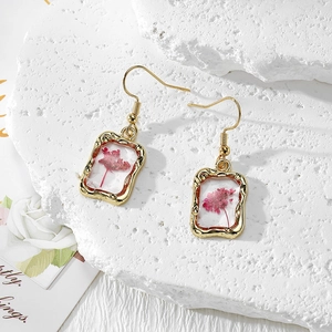 Elegant gold earrings featuring real pink dried flowers in rectangular resin frames