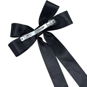 Detail of silver metal spring clip and black satin texture on long ribbon hair bow
