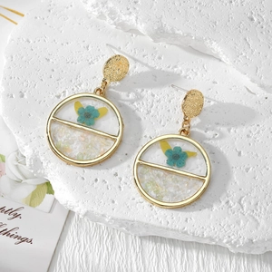 Handmade geometric resin earrings with blue dried flowers and green gravel on stone