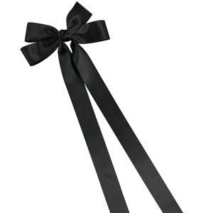 Detail of long black satin ribbon bow hair clip with smooth silky texture