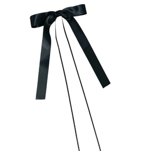 Close-up of black satin ballet-style bow hair clip with long ribbons on white backdrop
