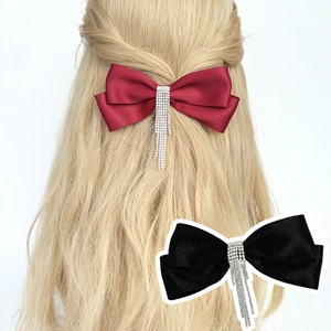 Vue détaillée de barrettes à nœud élégantes avec pompons en strass en satin rouge et noir