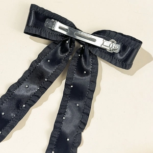 Close-up of the silver metal spring clip on a vintage satin bow hairclip with pleated edges