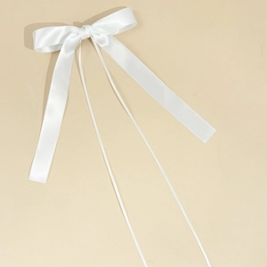 Close-up of white satin bow hair clip with long ribbons and elegant silk texture
