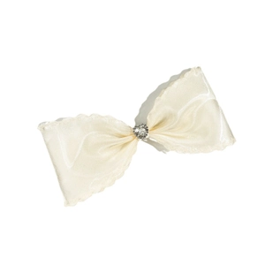 Barrette nœud crème avec cœur en strass et bords satinés ondulés sur fond blanc
