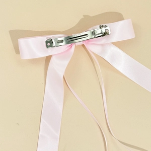 Detail view of pink satin bow hair clip with long ribbons and silver spring fastener