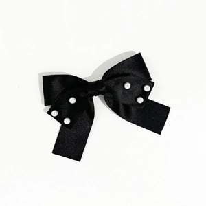 Détail du nœud papillon en satin noir élégant avec perles blanches sur fond blanc