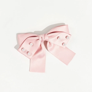 Gros plan d'une barrette nœud en satin rose avec perles blanches sur fond blanc