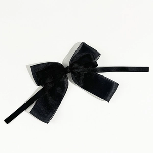 Détail de la pince à cheveux noeud en satin noir multicouche avec de longs rubans fins
