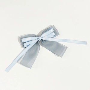 Détail d'une pince à cheveux avec nœud bleu en organza et satin au fini élégant