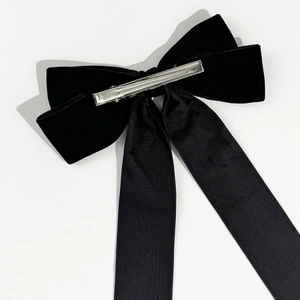 Detail of a large black velvet bow hair clip with long ribbons and metal spring clip