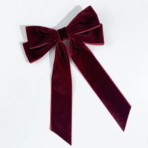 Detailed close-up of a burgundy velvet bow hair clip with elegant long ribbon tails