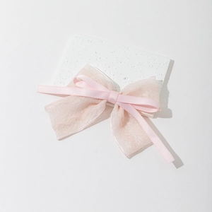 Gros plan sur le nœud papillon en dentelle rose avec rubans multicouches et tissu doux