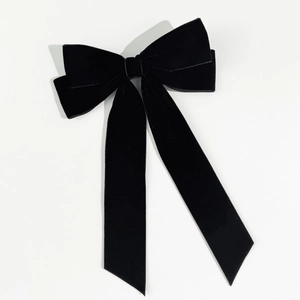 Detailed close-up showing texture of black velvet bow hair clip with long ribbons