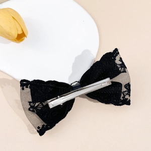 Barrette noeud en dentelle noire élégante avec strass argenté sur fond beige