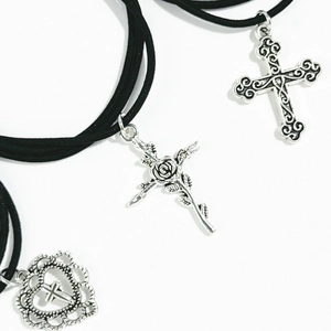 Detailed macro of vintage silver heart and rose cross pendants on black cord necklaces