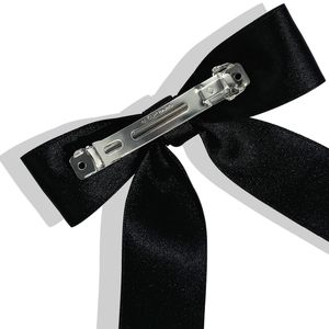Détail de la barrette en métal argenté avec gravure Paris sur un nœud en satin noir