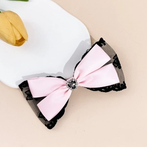 Détail de la barrette en satin rose et dentelle noire avec pierre en forme de cœur