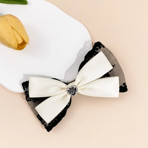 Gros plan détaillé d'une barrette noeud en dentelle avec une pierre noire en forme de coeur