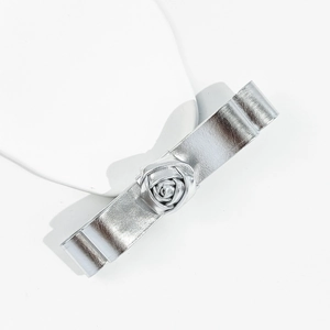 Dettaglio dell'elegante fermaglio per capelli in pelle argentata con una rosa 3D