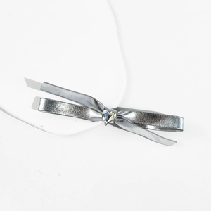 Dettaglio di un fiocco per capelli in metallo argento con cristallo a forma di cuore