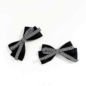 Détail macro de barrettes à nœud en satin noir avec ruban à carreaux noir et blanc élégant