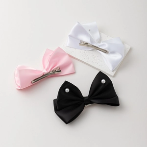 Trois barrettes à nœuds en satin rose blanc et noir avec détails en perles vue 45 degrés