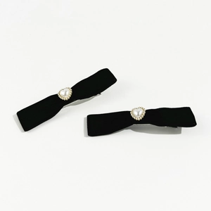 Close-up of velvet bow hair clips with pearl heart accents on a white background