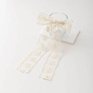 Elegant cream lace flower bow hair clip with long streamers on a white background