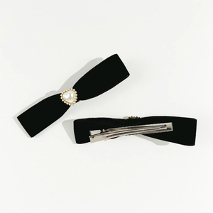 Close-up of black velvet bow hair clips with heart-shaped pearls and metal duckbill clips