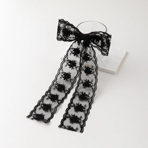 Detail of elegant black lace bow hair clip with embroidered flowers and long ribbons