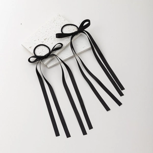 Detail showing two black ribbon bow hair ties on a textured white stone display