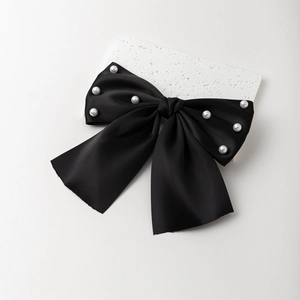 Barrette élégante en satin noir avec nœud et perles sur un socle en pierre