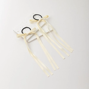 Ballet style cream silk ribbon bow hair tie with long streamers on stone surface
