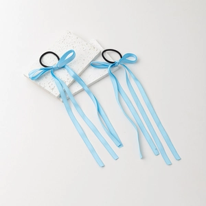 Detail of light blue satin ribbon bow hair ties with long streamers on a white stone base