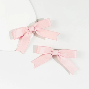 Close-up of light pink satin bow hair clips with refined silk texture and swallowtail cut