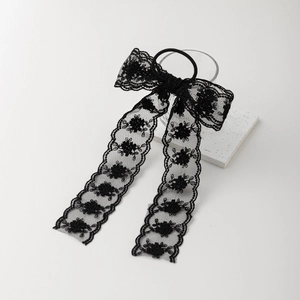 Détail d'un chouchou en dentelle noire élégante avec broderies florales et rubans