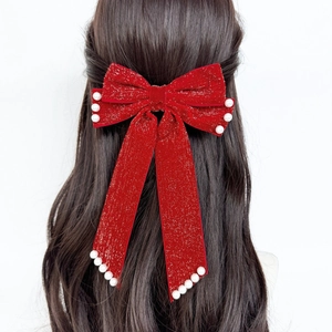 Detail of red velvet bow hair clip with white pearls and sparkling silver glitter