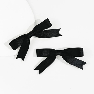 Close-up of black satin bow hair clips with swallowtail ends on a white background