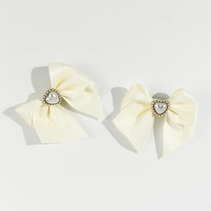 Detail of cream satin bow hair clips featuring heart-shaped pearls and gold beads