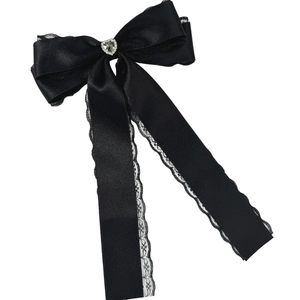 Detail of black satin bow hair clip with white lace trim and heart crystal center