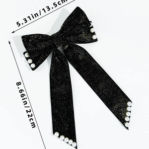 Macro detail of black velvet bow hair clip with faux pearls and gold glitter accents