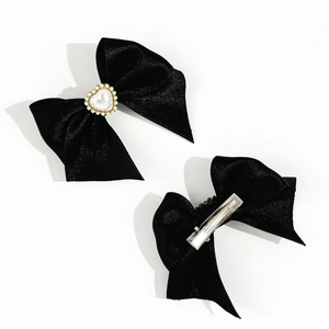 Detail view of black ribbon bow hair clips with heart pearl and metal duckbill clip
